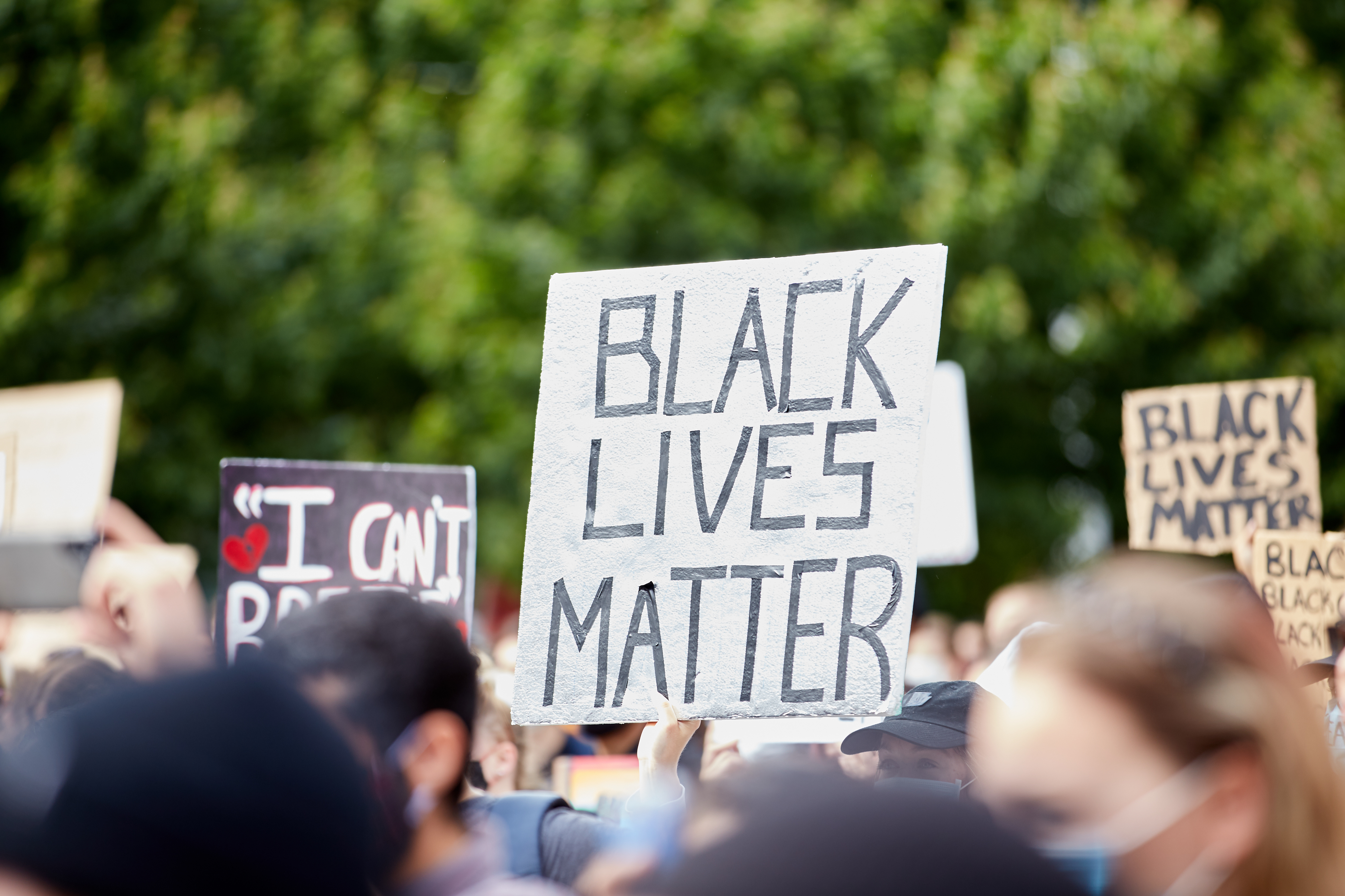 Cartaz "BLACK LIVES MATTER" entre outros numa marcha